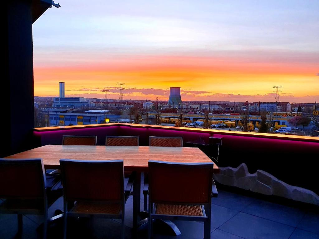 d'une table et de chaises sur un balcon avec vue sur le coucher du soleil. dans l'établissement Storchennest, à Dresde