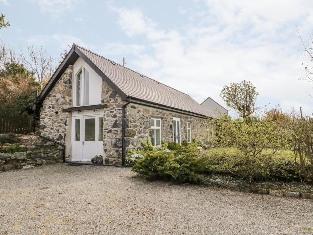 an old stone cottage with a white door at Beudy Hywel in Caernarfon