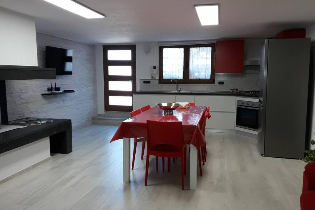 a kitchen with a red table and red chairs in a room at Incantos Charme B&B & Apartment in Tortolì