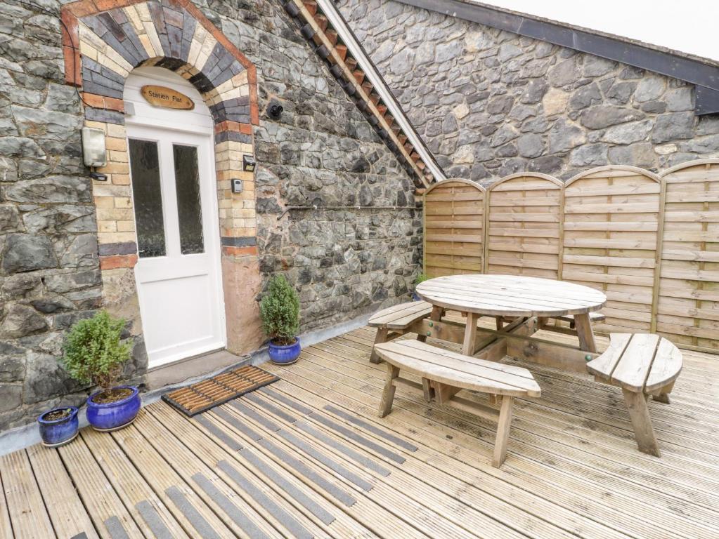 a wooden deck with a table and two benches at Station Flat in Betws-y-coed