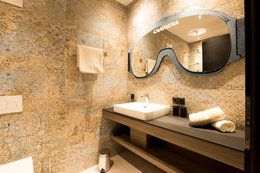 ein Bad mit einem Waschbecken und einem Spiegel in der Unterkunft DER WOLF -Suiten in Sankt Anton am Arlberg