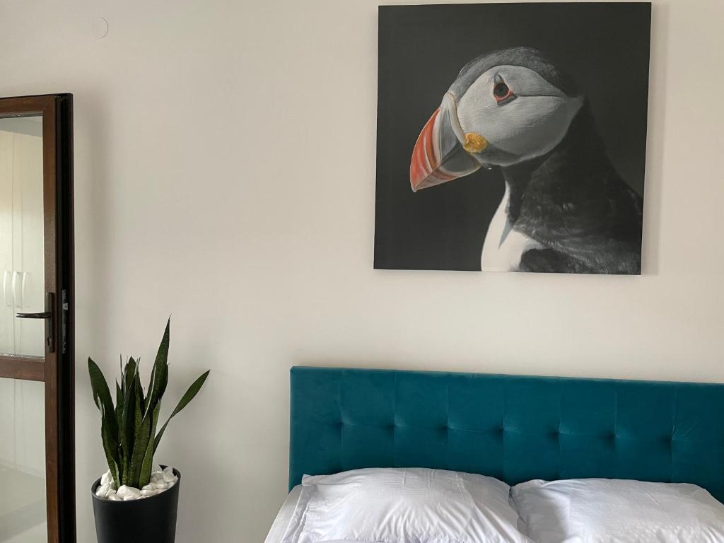 a painting of a bird on a wall next to a bed at Le Nid - your central destination in Iaşi