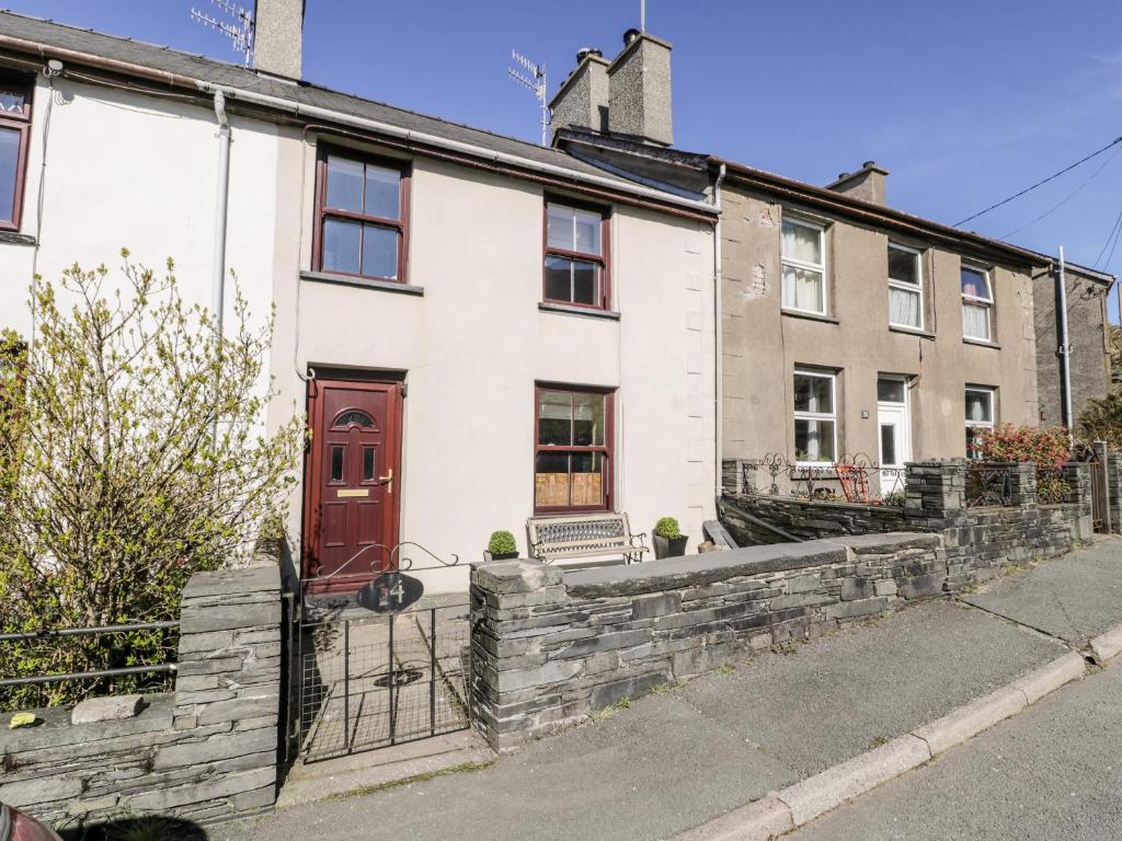 una casa blanca con una puerta roja en una calle en Miners Cottage en Blaenau-Ffestiniog