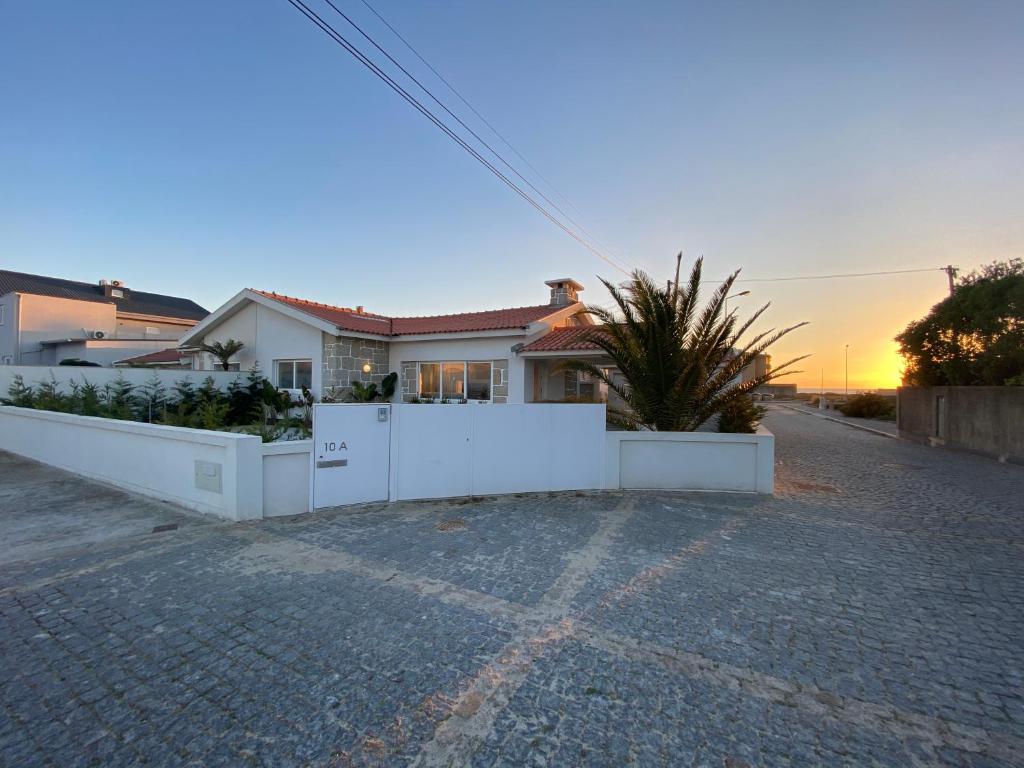 ein Haus mit einem weißen Zaun in einer Einfahrt in der Unterkunft Arvore Beach House in Porto