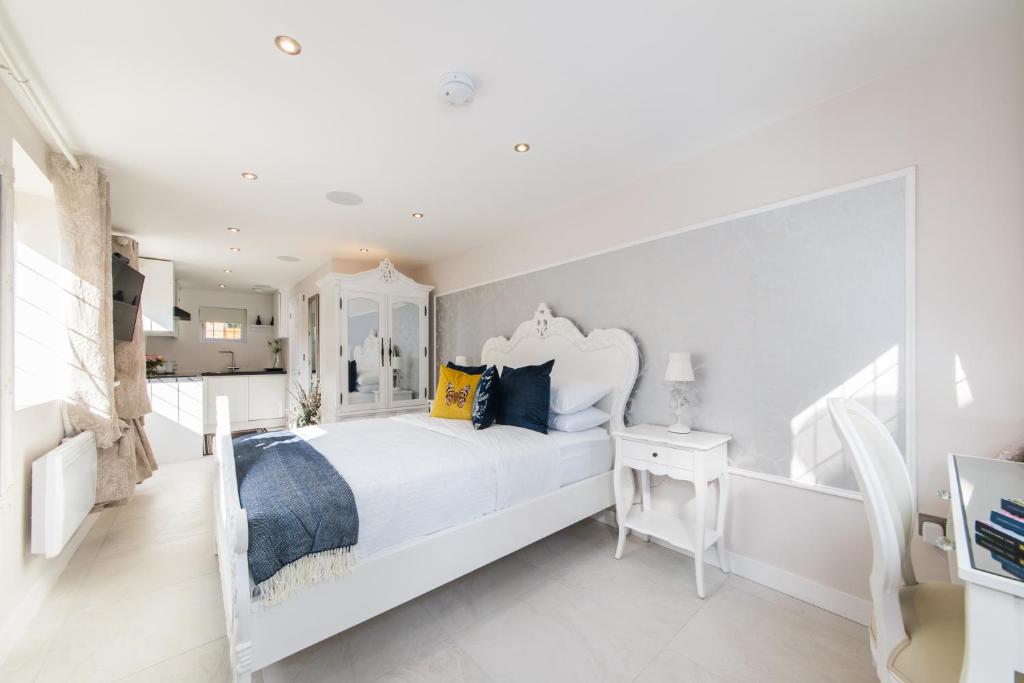 ein weißes Schlafzimmer mit einem weißen Bett und einem Tisch in der Unterkunft Elimonn Bloom in Kent