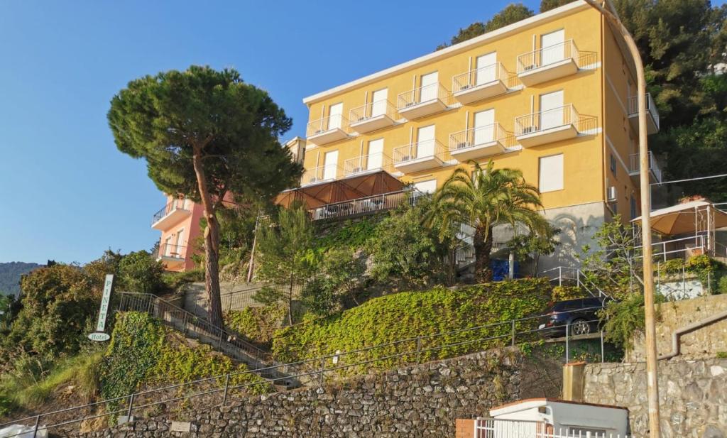 een geel gebouw aan de zijkant van een heuvel bij Hotel Pineta in Laigueglia