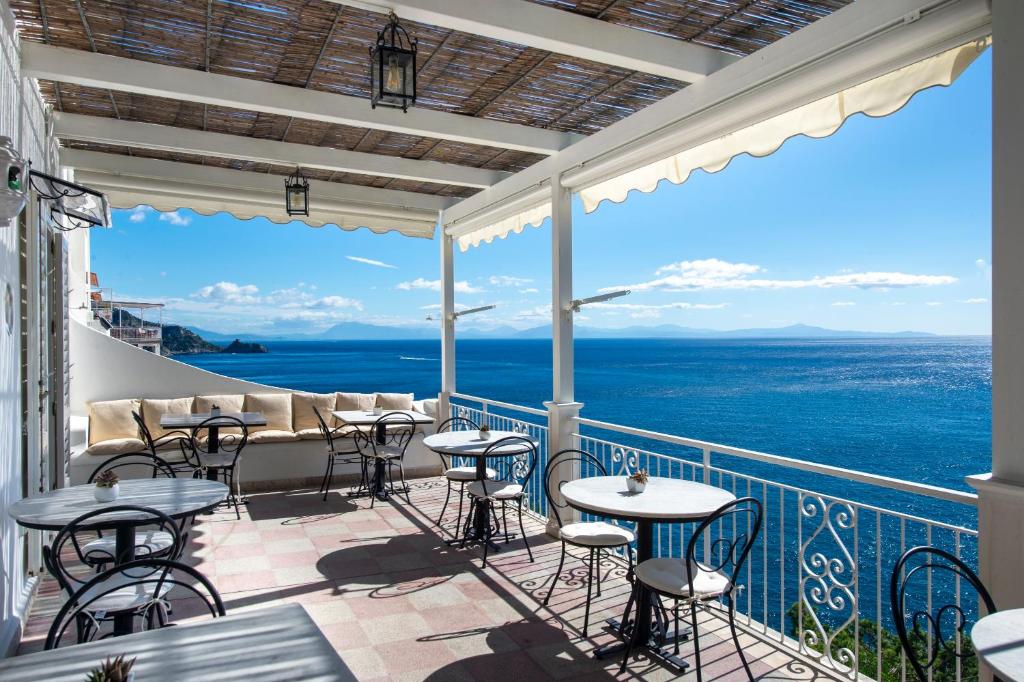 a balcony with tables and chairs and the ocean at Maresca Hotel Praiano in Praiano