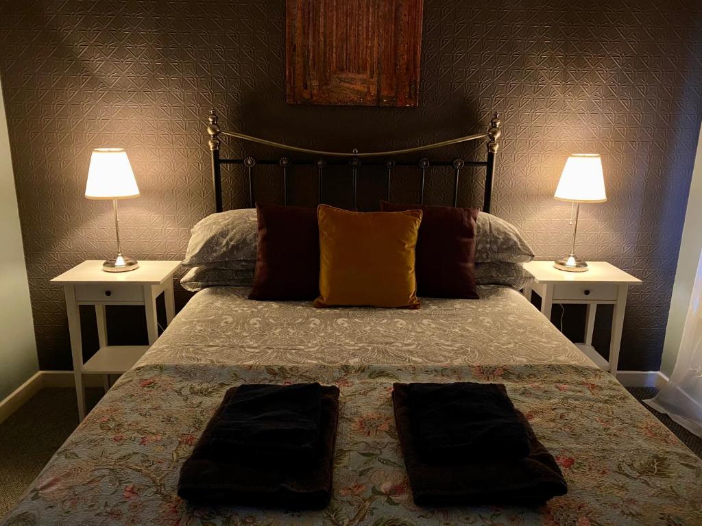 a bedroom with a bed with two lamps on two tables at Holly Cottage in Glencoe