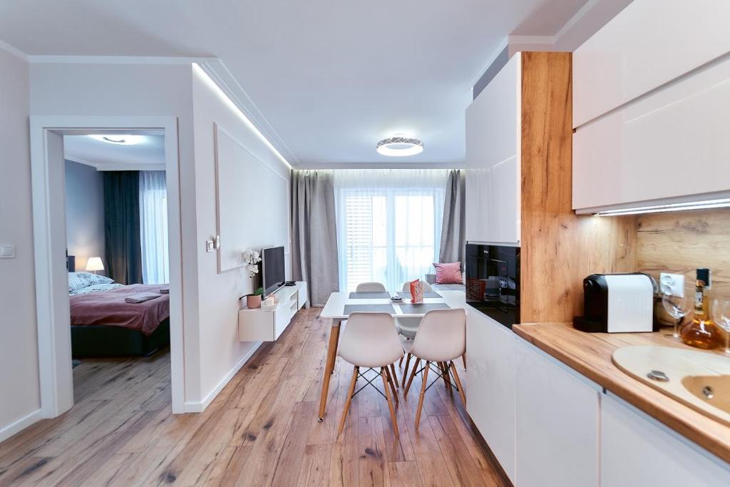 a kitchen and living room with a table and chairs at LAGUNA Apartament Polanica Residence 28 in Polanica-Zdrój