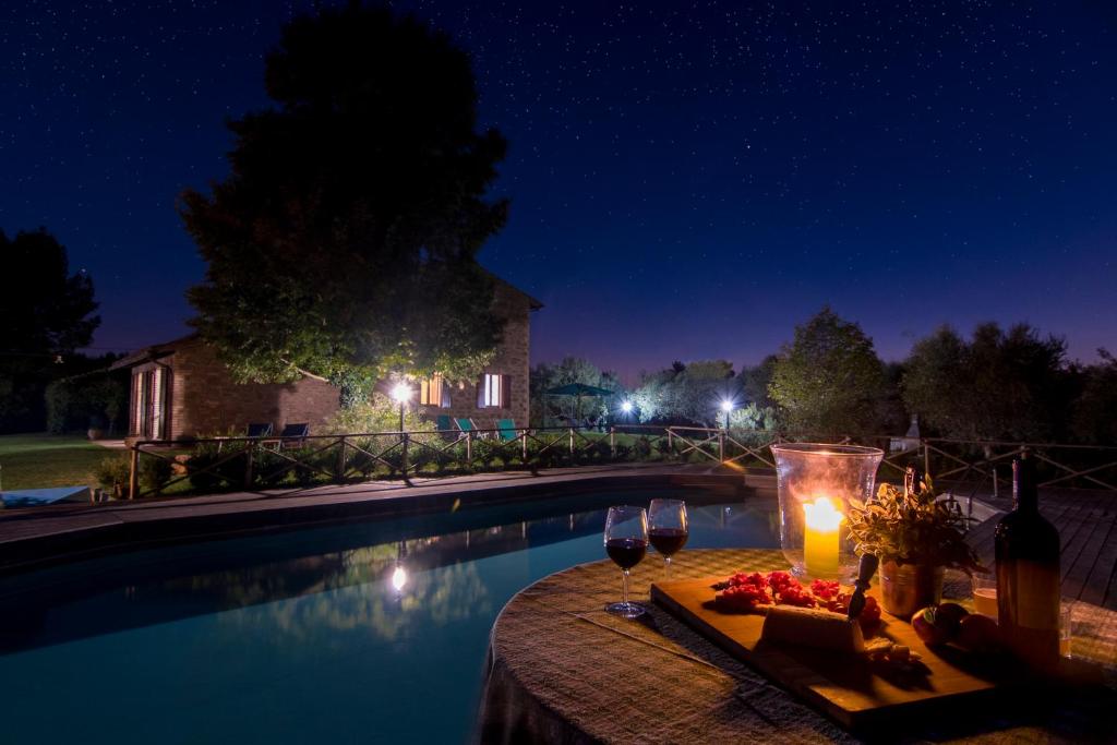 a table with wine glasses and a candle next to a pool at Agriturismo La Montagnola in Torgiano