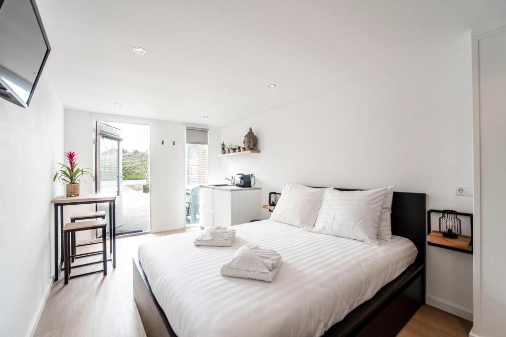 - une chambre avec un lit blanc et des serviettes dans l'établissement Little Buddha, à Zandvoort