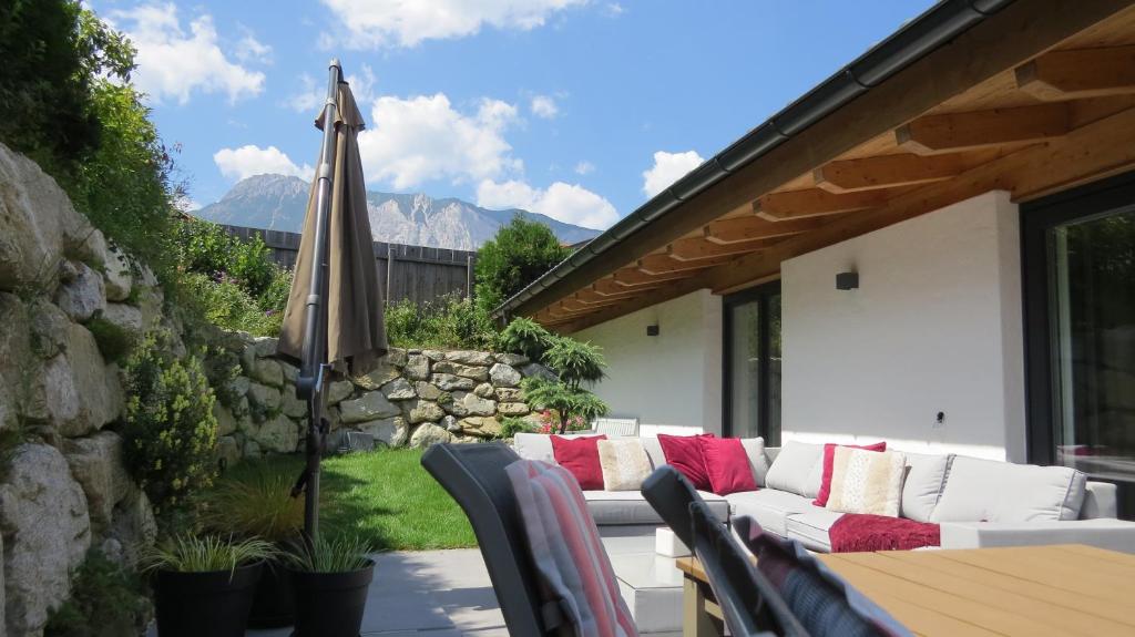 eine Außenterrasse mit einem Sofa und einem Sonnenschirm in der Unterkunft Chalet Hackl in Sautens