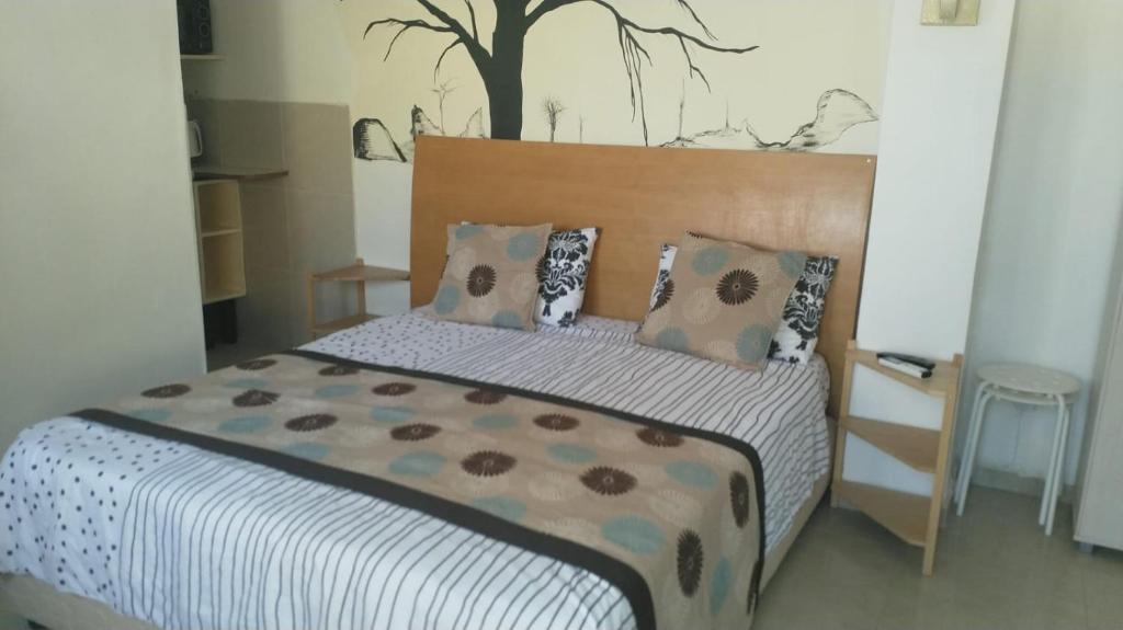 a bedroom with a bed with a tree behind it at Beatrice Hospitality in Neve Zohar