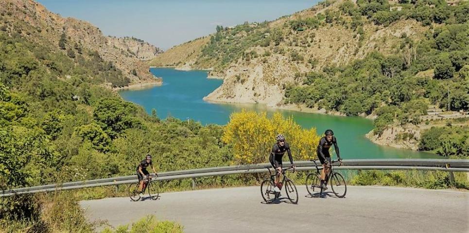 dwie osoby jadące na rowerach drogą w pobliżu rzeki w obiekcie TODOSIERRANEVADA ZONA BAJA - EDIFICIO ATLAS - VISTAS A LA MONTANA - Junto a los Telecabinas w mieście Sierra Nevada