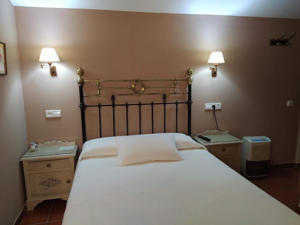 1 dormitorio con 1 cama blanca grande y 2 mesitas de noche en Apartahotel Montecaoru, en Arenas de Cabrales