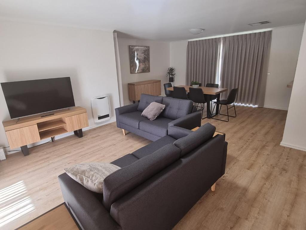 a living room with a couch and a flat screen tv at Mildura Holiday Homes - 15th Street in Mildura