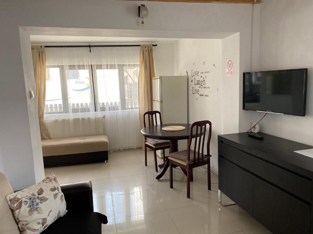 ブシュテニにあるCasa Antonia Busteniのテーブルと椅子とテレビのあるリビングルーム