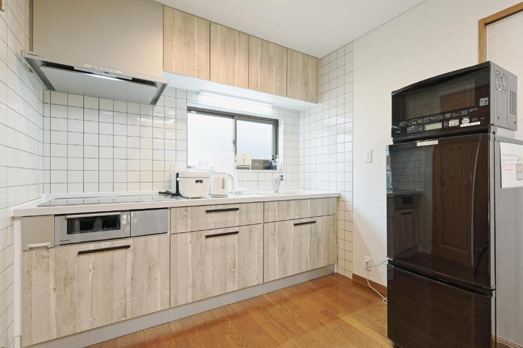 eine Küche mit Holzschränken und einem schwarzen Kühlschrank in der Unterkunft Mon Petit Chat in Kanazawa