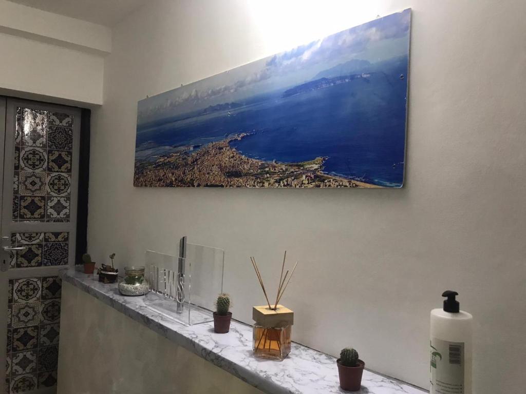 ein Gemälde an einer Wand über einem Tresen mit Pflanzen in der Unterkunft Affittacamere Le Isole in Trapani