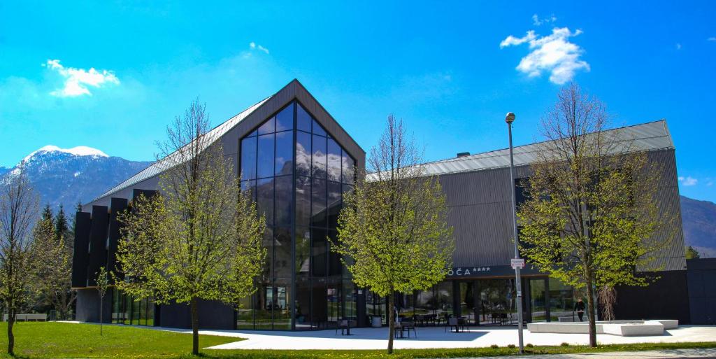 a large building with mountains in the background at Hotel Soča in Bovec