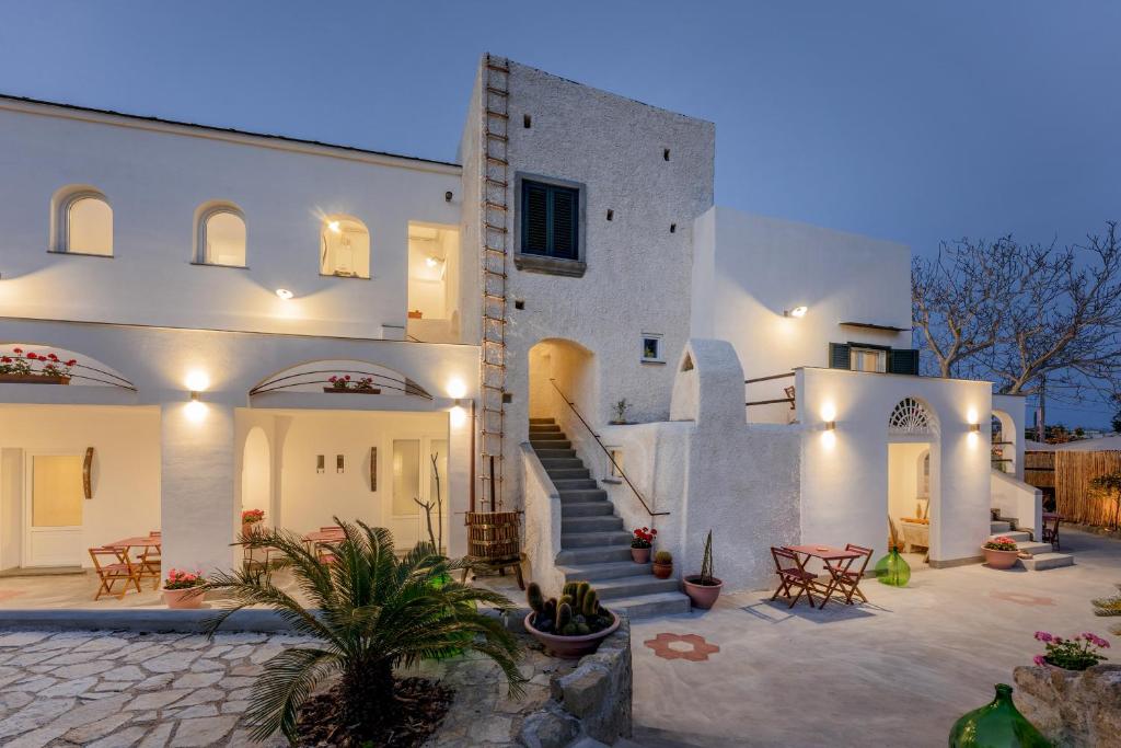 a white house with stairs and tables and chairs at Cala Cala Rooms,Restaurant & Farm Experience in Procida