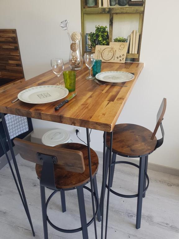 una mesa de madera con 2 sillas y platos. en La Rose des Sables, en Frontignan