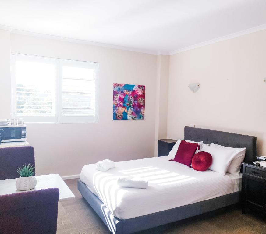 1 dormitorio con 1 cama blanca grande con almohadas rojas en Bay & Basin, en Sanctuary Point