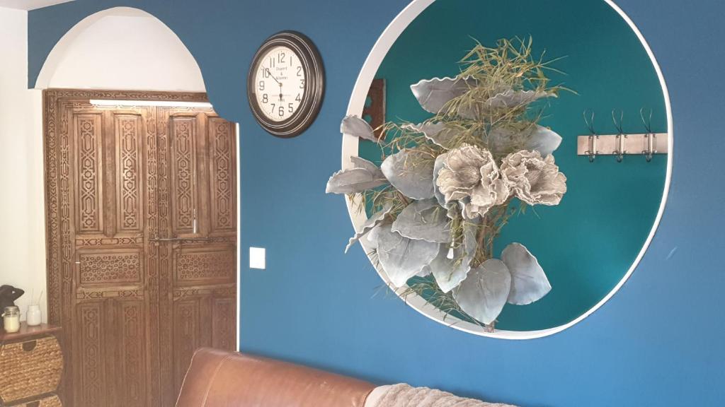 a mirror on a blue wall with a plant and a clock at JOLIE MAISON CONTEMPORAINE St Emilion in Néac