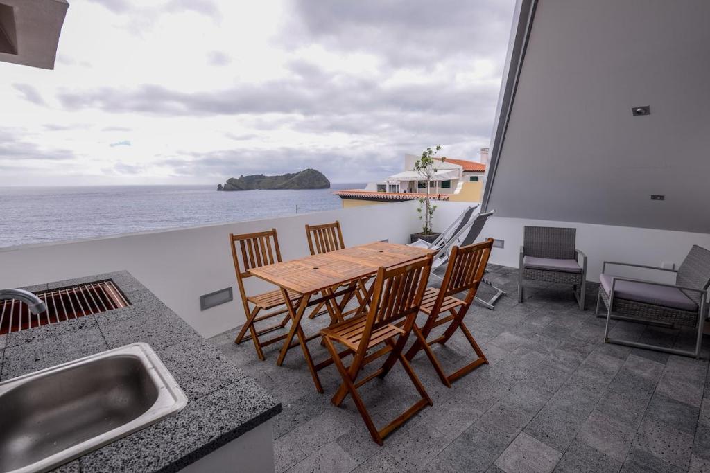 einen Balkon mit einem Tisch, Stühlen und Meerblick in der Unterkunft CASA DAS TAIPAS in Vila Franca do Campo