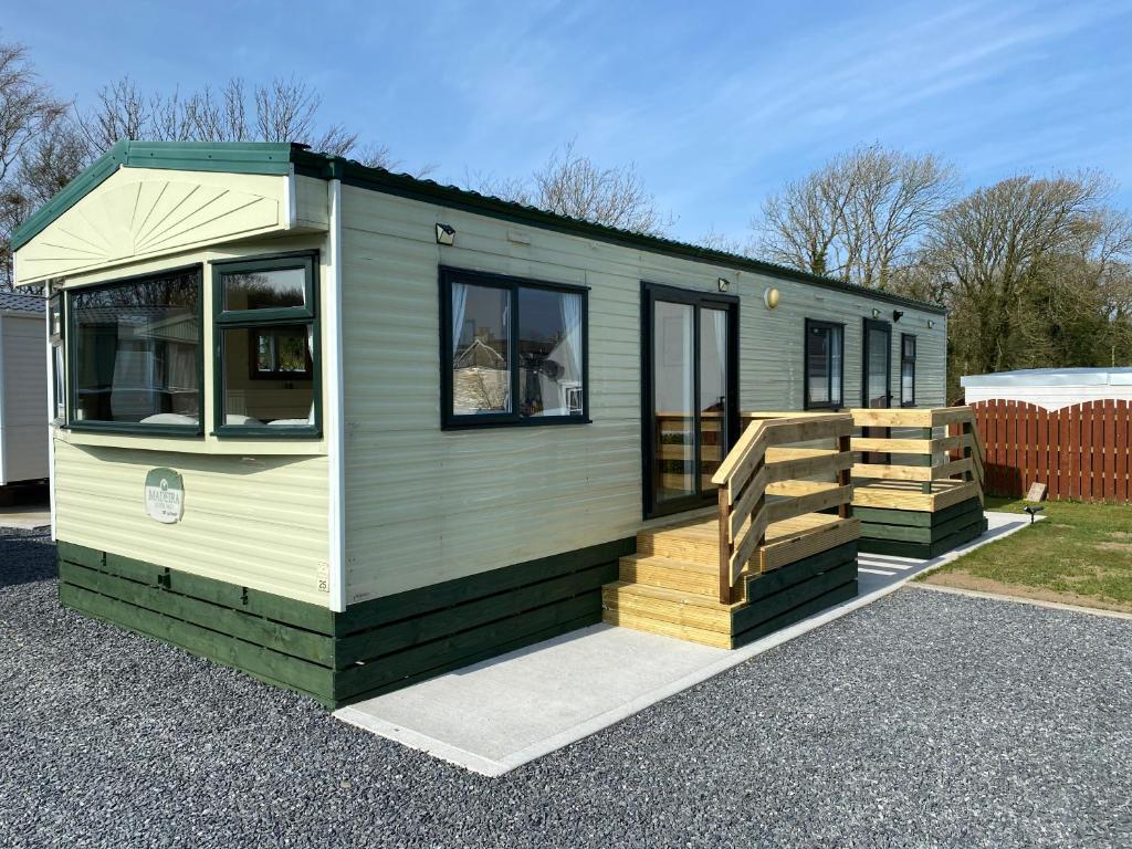 a green tiny house with a wooden deck at Happydays Caravan hire Whithorn 1 in Bailliewhir