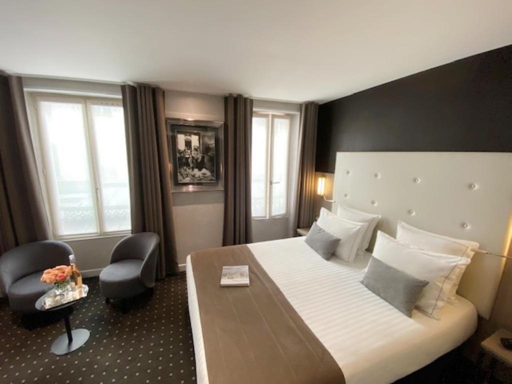 a hotel room with a large bed and a large window at Hotel de la Paix Tour Eiffel in Paris