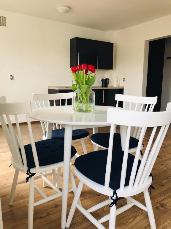 a white table and chairs with a vase of flowers on it at Apartament Marina Mazury in Węgorzewo