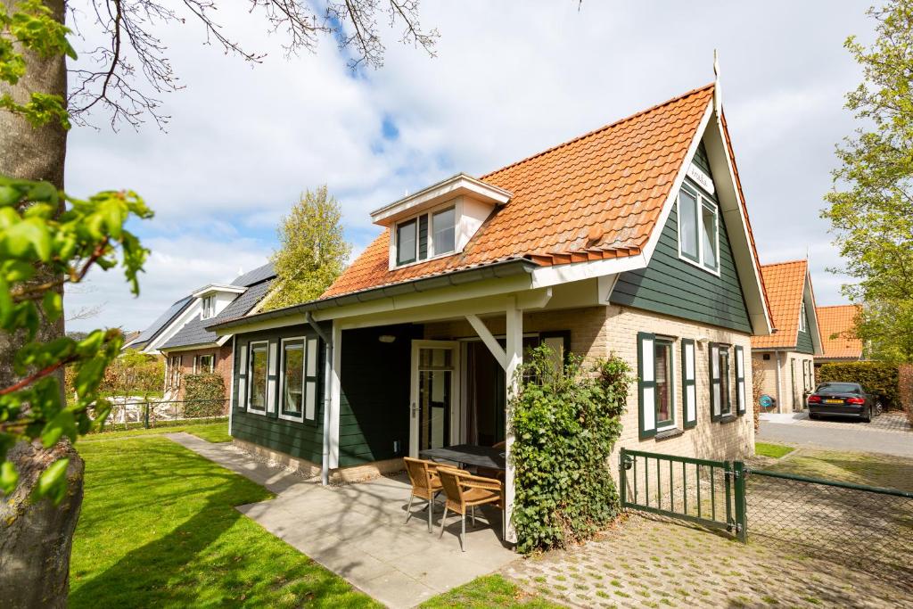 uma casa com um telhado verde e um pátio em Vakantiehuis Arcadia em Zonnemaire