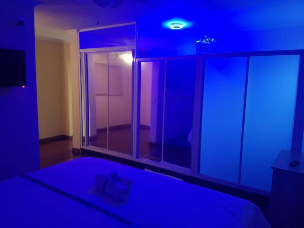 a bedroom with a blue light and a bed with a window at Khaya B&B in Cape Town