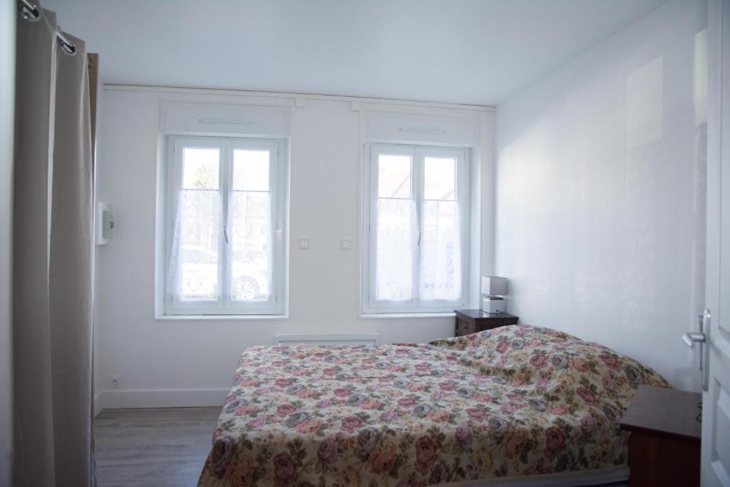 a white bedroom with a bed and two windows at Damville Centre in Damville
