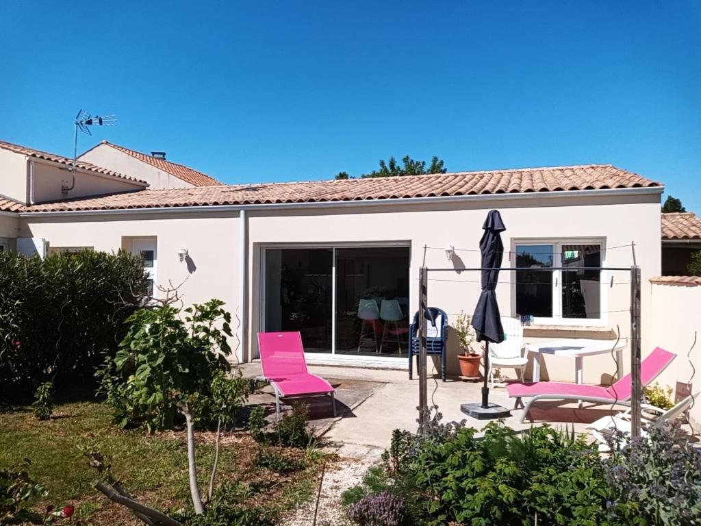 a house with pink chairs and an umbrella at Meublés des 3 îles in Châtelaillon-Plage