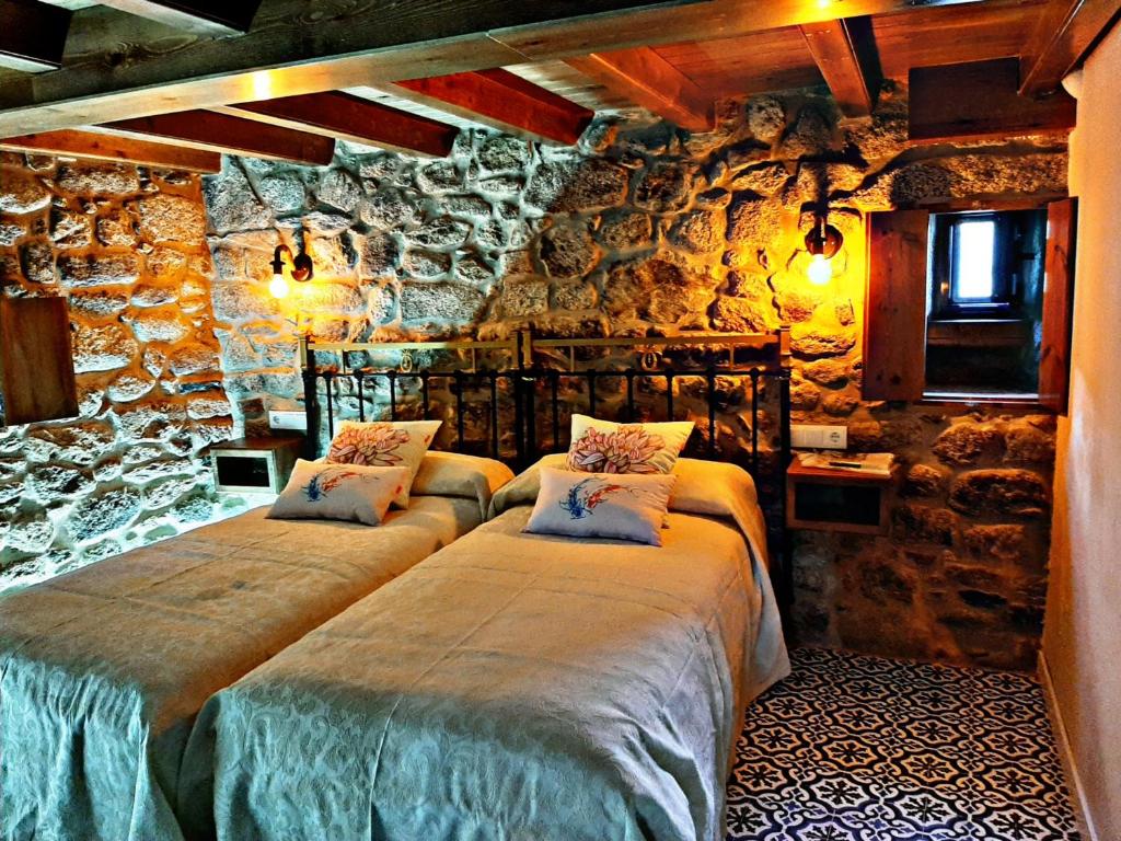 Dos camas en una habitación con pared de piedra. en Casa da Loura - Costa da Morte, en Dumbría