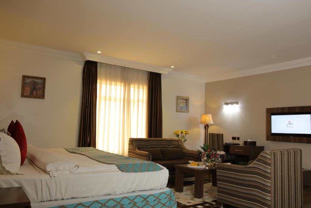 Habitación de hotel con cama y sala de estar. en Grand Pela Hotel & Suites, en Abuja