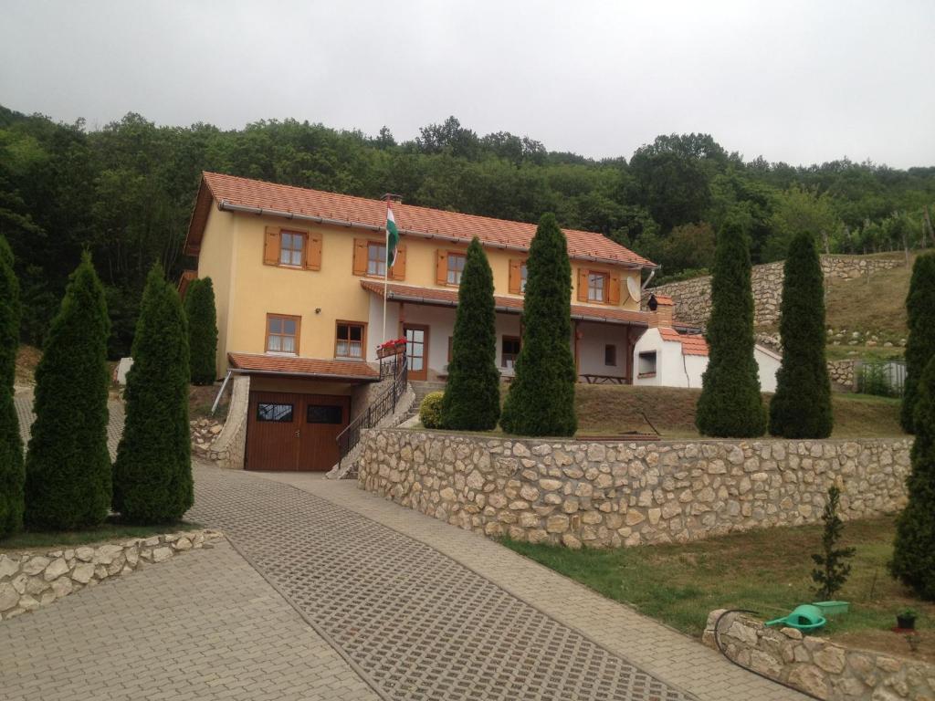 una casa grande con una pared de piedra y árboles en Judit Vendégház Sümeg, en Sümeg