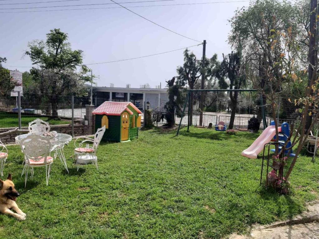 a dog laying in a yard with a table and a playground at Palio Villa in Paleo Tsifliki