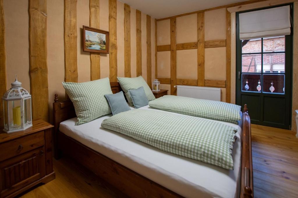 a bedroom with a bed with green and white pillows at Naturhof-Papiermühle 3 Bett-Zimmer Immergrün in Bollberg