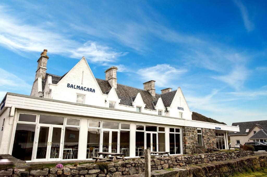a white building with a stone wall in front of it at Balmacara Hotel in Kyle of Lochalsh