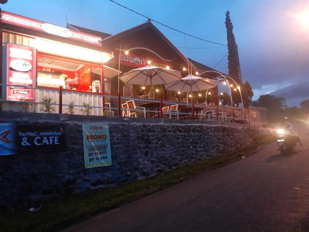 un edificio con una cafetería con mesas y sillas por la noche en SUWON homestay, en Mojokerto