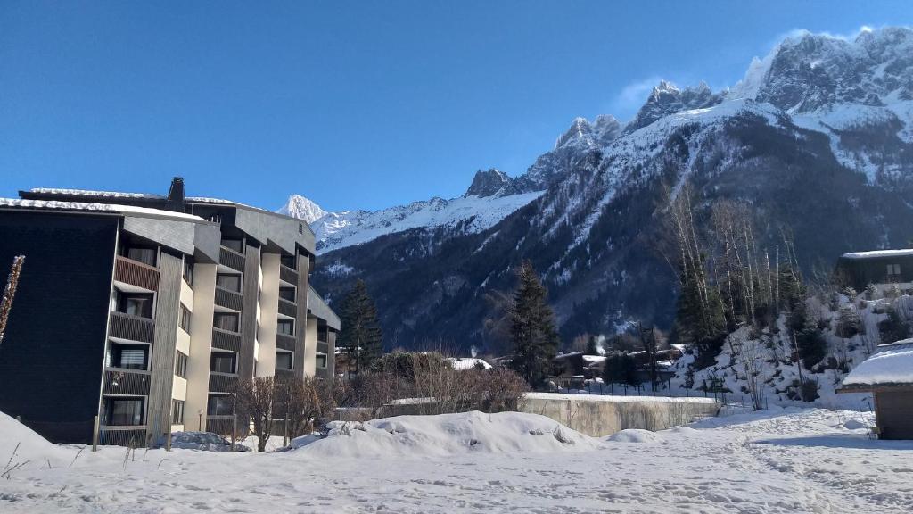 un bâtiment dans la neige devant une montagne dans l'établissement studio plein sud vue Mont Blanc CHAMONIX, à Chamonix-Mont-Blanc