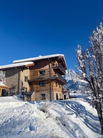 a large wooden building with snow on the ground at Bergheimat Tirol in Lermoos