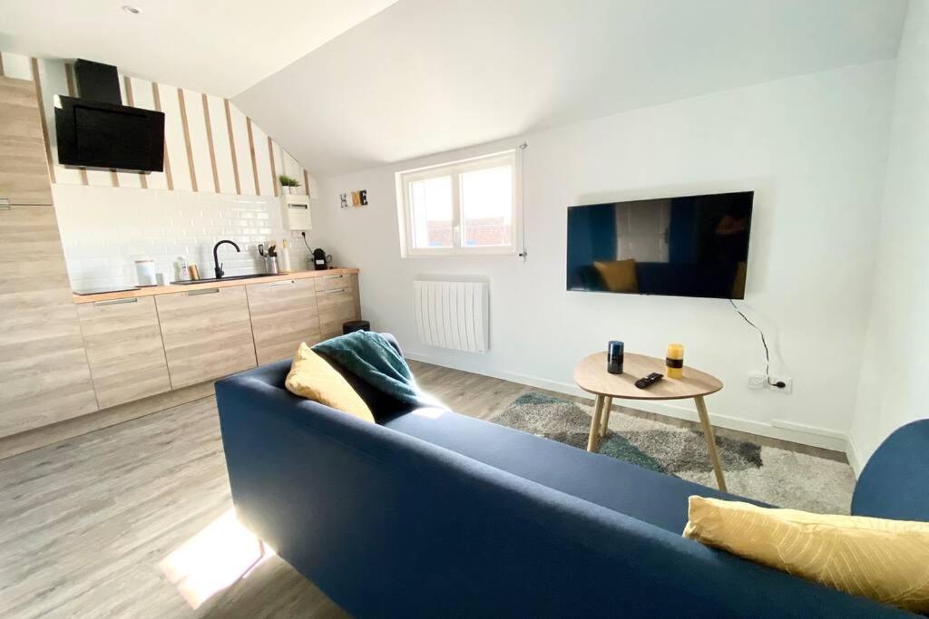 uma sala de estar com um sofá azul e uma mesa em Le Boisé Beauvaisien em Beauvais