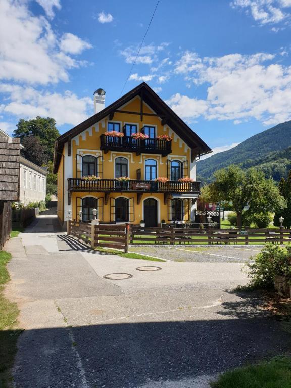 a yellow building with a balcony on the side of it at Pension Alte Mühle in Gmünd in Kärnten