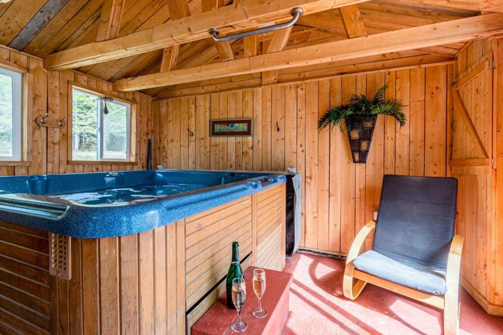 eine Whirlpool-Badewanne in einer Holzhütte mit einem Stuhl in der Unterkunft L'OASIS DU MASSIF - Spa, BBQ, foyer et plaisir ! in Saint-Paul-de-Montminy