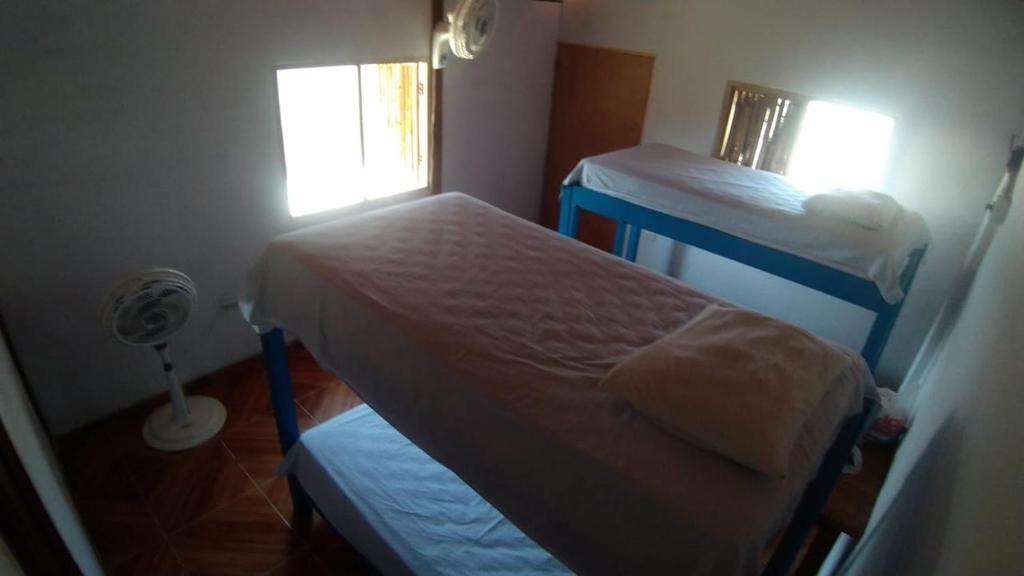 a small room with two beds and a window at Urantia Beach Hostel & Surf Camp in San Onofre
