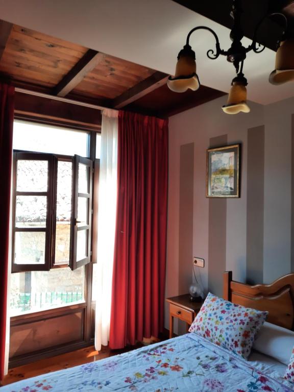 a bedroom with a bed with a red curtain and a window at Casa de Aldea Florentina in Arenas de Cabrales